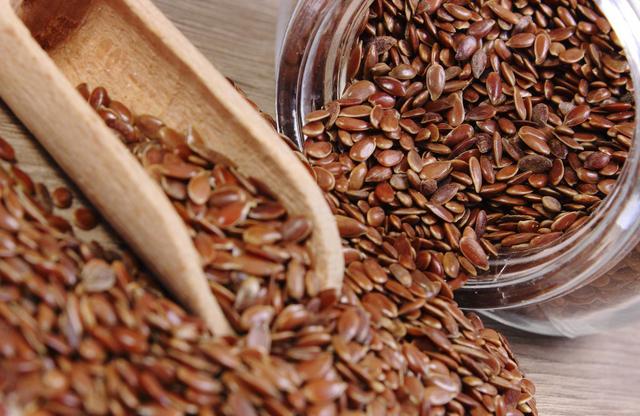Linseed spilling out of jar on wooden background
