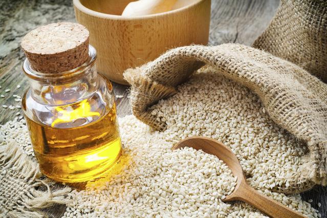 sesame seeds in sack and bottle of oil on table