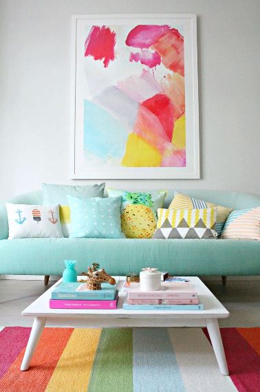 Το ριγέ πολύχρωμο χαλί περιέχει τα χρώματα του πίνακα και δημιουργεί αντίθεση με τον mint green καναπέ.