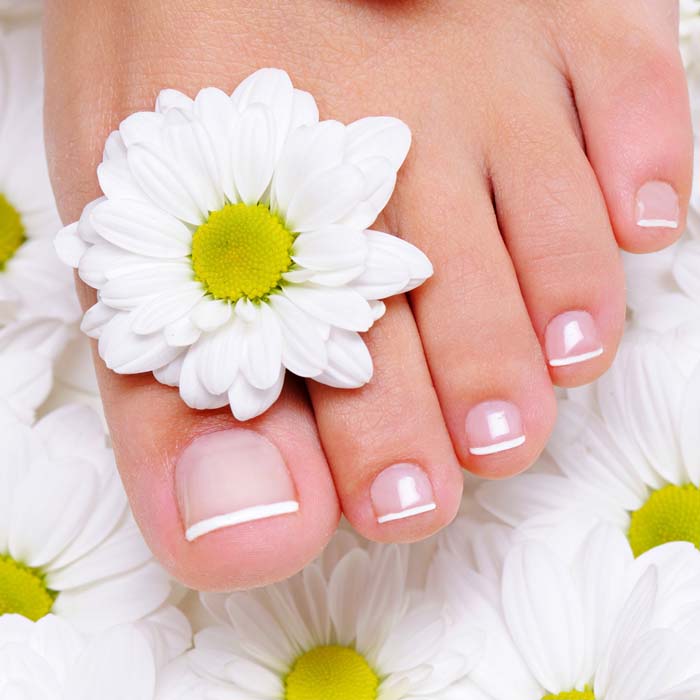female hand with beautiful french manicure on the pure and clean foot