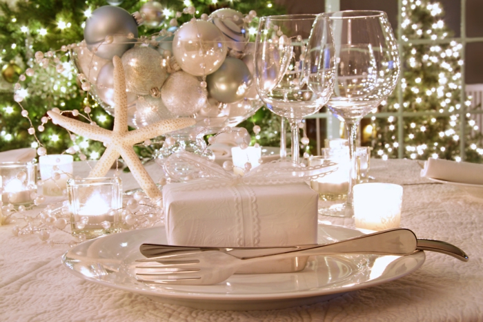 Elegantly lit holiday dinner table with wine glasses and white ribboned gift